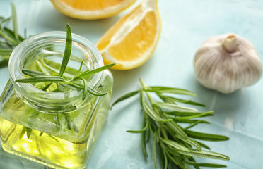 Glass jar with oil and fresh rosemary on table