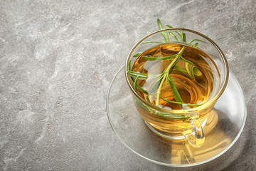 Hot tea with fresh rosemary in glass cup on grey table