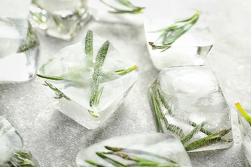 Rosemary frozen in ice cubes on light grey background