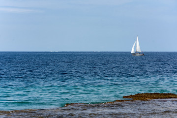 Sailboat glides across the bright blue ocean