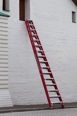 Red ladder in front of a white wall