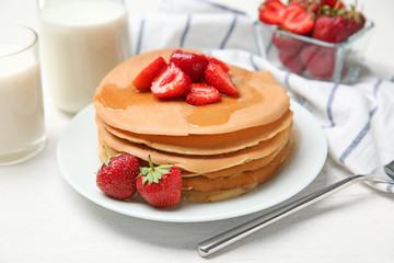 Delicious pancakes with strawberries and honey on table