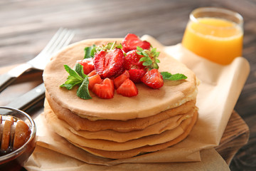 Delicious pancakes with strawberries on table