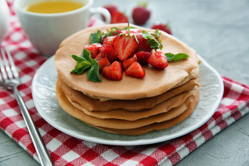 Plate with delicious pancakes and strawberries on light table