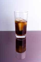 Cola and ice cubes in glass on white background with selective focus and crop fragment