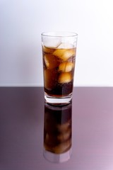 Cola and ice cubes in glass on white background with selective focus and crop fragment