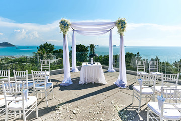 Wedding venue setting, Arch and altar decorated with roses, flowers, ocean background