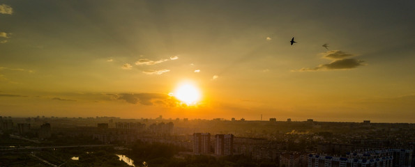 Aerial drone view of sunset over the housing estate, bird's eyes view, silhouettes of high-rise buildings on the background