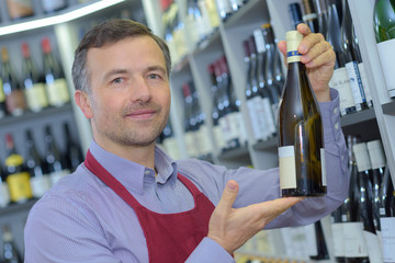 confident male sommelier examining wine bottle