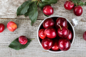 Plums with leafs on wooden background.