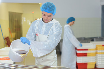 Factory worker pouring liquid from bucket