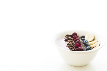 Smoothie bowl with fresh berries, banana, chia seeds and chocolate for healthy vegan and vegetarian diet breakfast