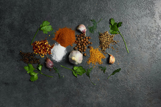  Various herbs and spices on black background. Salt, Garlic,turmeric, pepper peas. Top view with copy space.