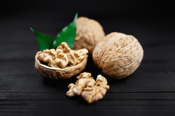 Walnut and walnut kernels and whole walnuts on rustic black wooden background.