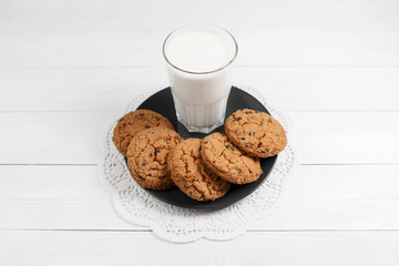 Tasty cookies and glass of milk on rustic white wooden background.