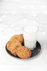 Tasty cookies and glass of milk on rustic white wooden background.
