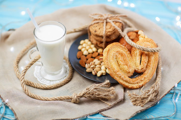 Glass of milk and tasty cookies on the vintage blue wooden background.