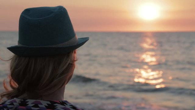 Woman with a hat on the beach looking at sunset / sunrise during her holiday in Australia.