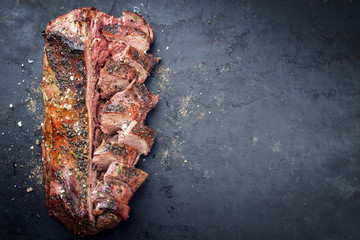 Traditional barbecue aged saddle of venison marinated as top view on an old rustic board with copy space right