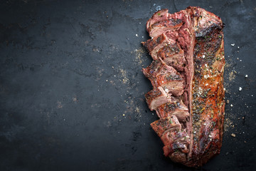 Traditional barbecue aged saddle of venison marinated and sliced as top view on an old rustic board with copy space left