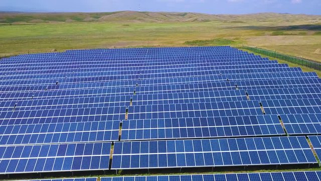 Solar panels and renewable energy farm. Aerial drone video footage looking down onto rows of solar panels in a renewable energy farm in the English countryside in bright dusky sunshine