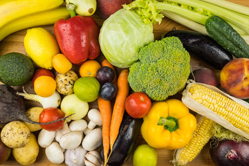 Close-up top view image of fresh organic vegetables and fruit. Locally grown bell pepper, corn, carrot, mushrooms and other natural vegan food laying on table.