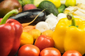 Close-up view of fresh organic bell peppers, tomatoes and other vegetables. Locally grown natural vegan food laying on table.