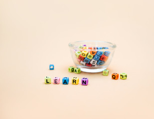 Learn : Colorful cube letters in Glass cup on orange Background