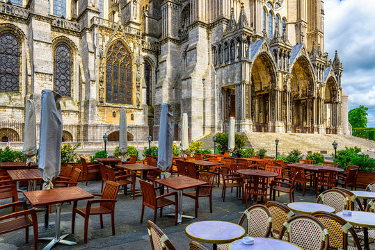 Old street with Chartres Cathedral and tables of cafe in a small town Chartres, France