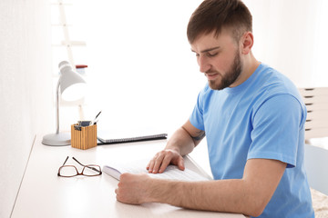 Young man reading book at home