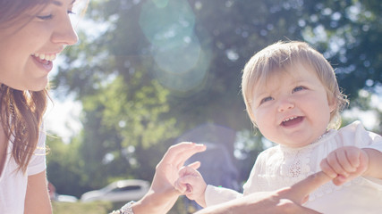 Portrait of beautiful toddler laughing and smiling with their mother outdoors
