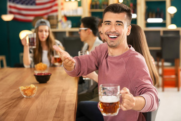 Young man with friends drinking beer in bar