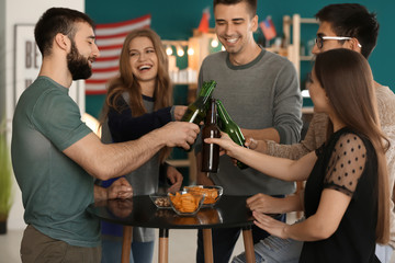 Group of friends clinking bottles with beer in bar