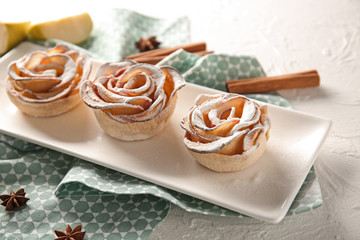 Plate with tasty apple roses from puff pastry on table