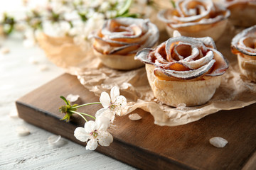 Tasty apple roses from puff pastry on wooden board