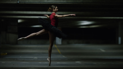 Portrait of ballet dancer dancing in an underground car park at night