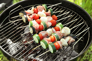 Skewers with juicy meat and vegetables on barbecue grill outdoors