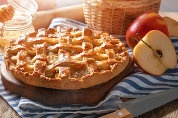 Wooden board with tasty apple pie on table