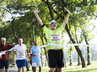 Happy senior running through the finish line