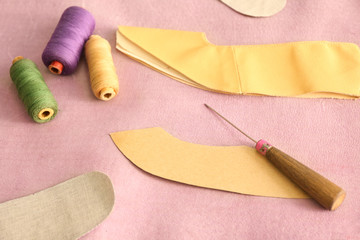 Paper template with awl and threads on leather in workshop
