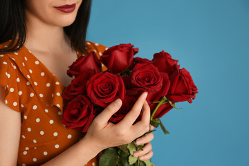 Woman holding beautiful roses on color background