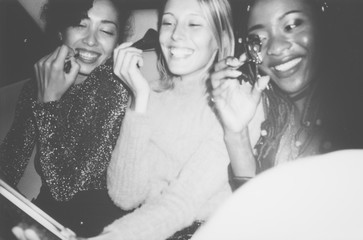 Diverse women applying makeup in a backseat