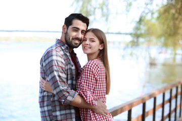 Happy young couple near river in park on spring day