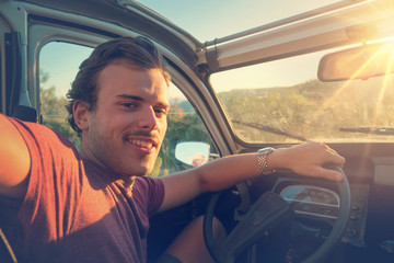 Fototapeta premium Young man in a car at sunset