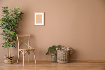 Wooden chair with wicker basket and plant near color wall