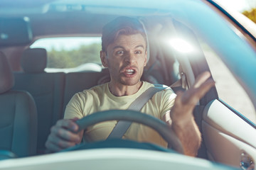 Furious man. Emotional man feeling extremely furious while driving near crazy dangerous driver