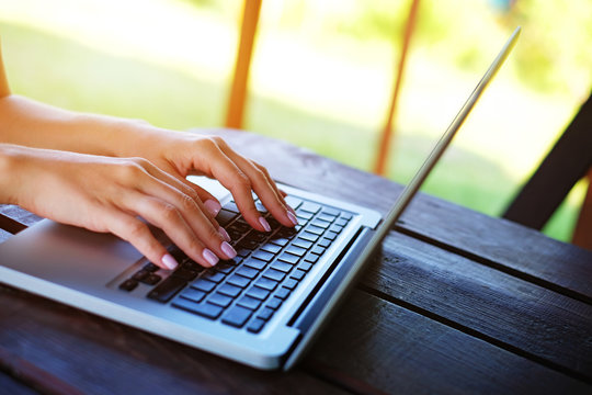 Woman's hands typing on laptop outdoors