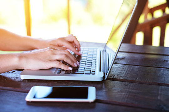 Woman's hands typing on laptop outdoors
