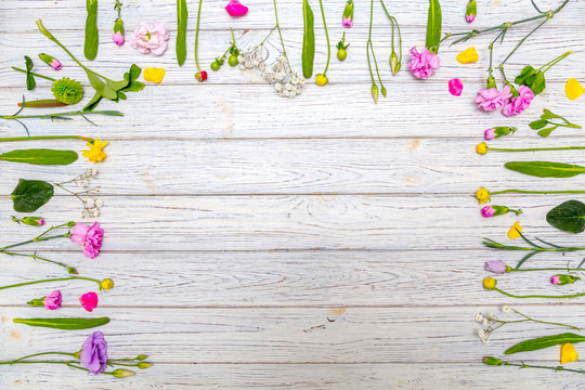 Flower Frame With White, Yellow, Green And Purple Flowers On A Wooden Background, Flatlay