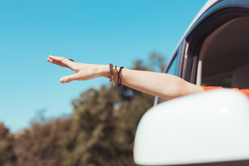 Dress and bracelets. Woman wearing orange dress and accessories taking hand out of window during...